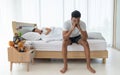 Family problem and relationship concept. Young Asian upset man  sitting on the bed the woman is on background Royalty Free Stock Photo