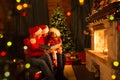 Family read stories sitting on coach in front of fireplace in Christmas decorated house interior