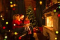 Family read stories sitting on sofa in front of fireplace in Christmas decorated house interior