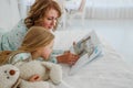 Family reading bedtime. Pretty young mother reading a book to her daughter. Mother reads a fairy tale to her daughter. A Royalty Free Stock Photo