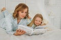 Family reading bedtime. Pretty young mother reading a book to her daughter. Mother reads a fairy tale to her daughter. A Royalty Free Stock Photo