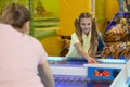 Family recreation concept. Happy teen girl playing air hockey with her mother at kids entertainment center
