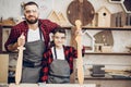 Father and son playing knights with wooden DIY swords at carpenter workshop Royalty Free Stock Photo