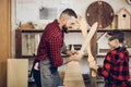 Father and son playing knights with wooden DIY swords at carpenter workshop Royalty Free Stock Photo