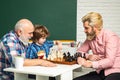 Family relationship between grandfather father and son. Grandpa teaching school boy playing chess, pupil child. Portrait