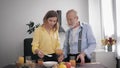 Family relationship, happy peppy old man prepares a delicious breakfast in the kitchen with healthy products, mixes with