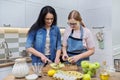 Mom and teen daughter cooking apple pie together at home kitchen Royalty Free Stock Photo