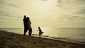 Family relaxing beach vacation. Parents looking kid playing at morning sea shore Royalty Free Stock Photo