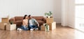 Family relaxing on floor in new home with cardboard boxes Royalty Free Stock Photo