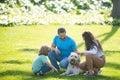 Family relaxing in garden with pet dog. The concept of a happy family. Parents and children on vacation playing together Royalty Free Stock Photo