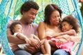 Family Relaxing On Outdoor Garden Swing Seat Royalty Free Stock Photo