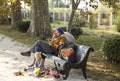 Family resting on a bench in the Park. The child plays with toys next to his parents