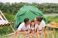 Family resting near the river in nature park, lying on ground near the tent, enjoying nature and fresh air near the water on Royalty Free Stock Photo