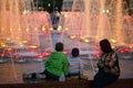 Family resting by the night fountain with backlight Royalty Free Stock Photo