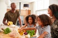 Family Returning Home From Shopping Trip Unpacking Plastic Free Grocery Bags