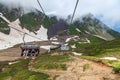 Family rides on cable way chair ski lift in Gorky Gorod mountain resort at spring. Caucasus mountains. Aibga ridge cirque. Scenic