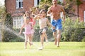 Family Running Through Garden Sprinkler Royalty Free Stock Photo