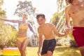 Family Running Through Water From Garden Sprinkler Having Fun Wearing Swimming Costumes Royalty Free Stock Photo