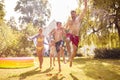 Family Running Through Water From Garden Sprinkler Having Fun Wearing Swimming Costumes Royalty Free Stock Photo