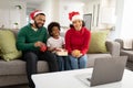 Family in Santa hat waving while having a video chat on laptop at home Royalty Free Stock Photo