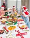 Family in santas hats toasting wine glasses at dining table