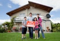 Family selling their home holding for sale sign Royalty Free Stock Photo