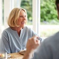 Family With Senior Mother And Adult Son Eating Brunch Around Table At Home Together