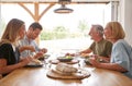 Family With Senior Parents And Adult Offspring Eating Meal Around Table At Home Together