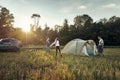 Family set up tent camp at sunset, beautiful summer landscape. Tourism, hiking and traveling in nature Royalty Free Stock Photo