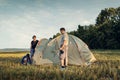Family set up tent camp at sunset, beautiful summer landscape. Tourism, hiking and traveling in nature Royalty Free Stock Photo