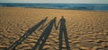 Family shadows on beach sand in sunrise. Shadows of three people holding a hand Royalty Free Stock Photo