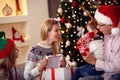 Family sharing gift on Christmas- smiling mother giving present