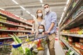 Family with shopping cart in masks at supermarket Royalty Free Stock Photo