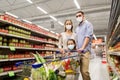Family with shopping cart in masks at supermarket Royalty Free Stock Photo