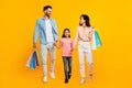 Family shopping concept. Happy caucasian parents and daughter carrying shopper bags, yellow background, full length Royalty Free Stock Photo