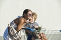 Family shopping concept. Happy parent go shopping with cute son. Mom pushing shopping cart with children in. Mother and Royalty Free Stock Photo