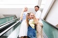 Parents And Daughter Smiling Standing On Moving Stairs In Mall