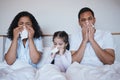 Family, sick and blowing nose in bedroom in home lying on bed together in house. Flu, parents and child wipe with tissue