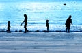 Family silhouetted on a blue evening beach Royalty Free Stock Photo
