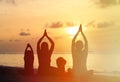 Family silhouettes doing yoga at sunset Royalty Free Stock Photo