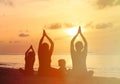 Family silhouettes doing yoga at sunset