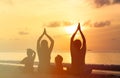 Family silhouettes doing yoga at sunset sea Royalty Free Stock Photo