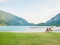 Family sit at Molveno lake and enjoy calm. Silent summer evening