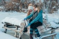 Family sits on a bench on the shore of a frozen lake