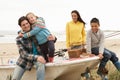 Family Sitting On Boat With Fishing Rod On Beach