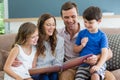 Family sitting on couch looking at photo album in living room at home Royalty Free Stock Photo