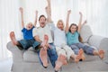 Family sitting on a couch and raising arms Royalty Free Stock Photo