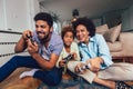 Family sitting on the couch together playing video games, selective focus Royalty Free Stock Photo