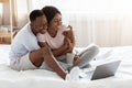 Family sitting in front of laptop on bed and hugging Royalty Free Stock Photo