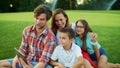 Family sitting on grass in park. Parents and children making video call with pad Royalty Free Stock Photo